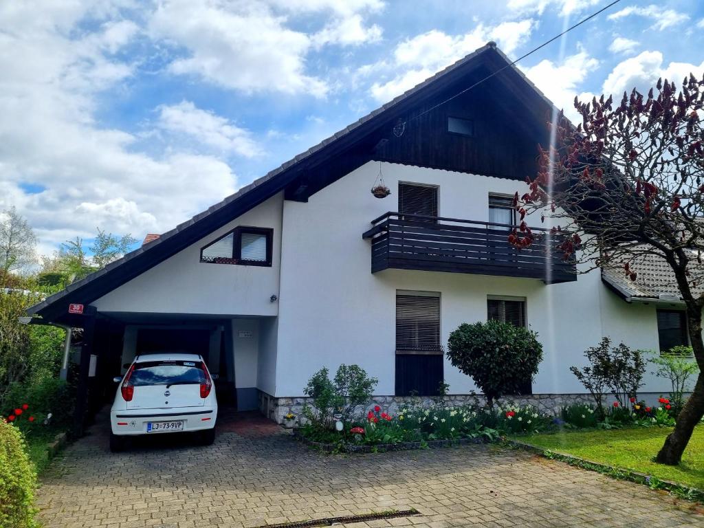 a white house with a car parked in the driveway at Apartma Take It Easy in Bled