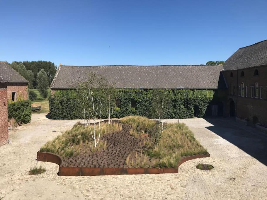 a garden in the middle of a yard with a building at Cottage entier : 6 à 8 personnes - La Ferme du Try in Frasnes-lez-Gosselies