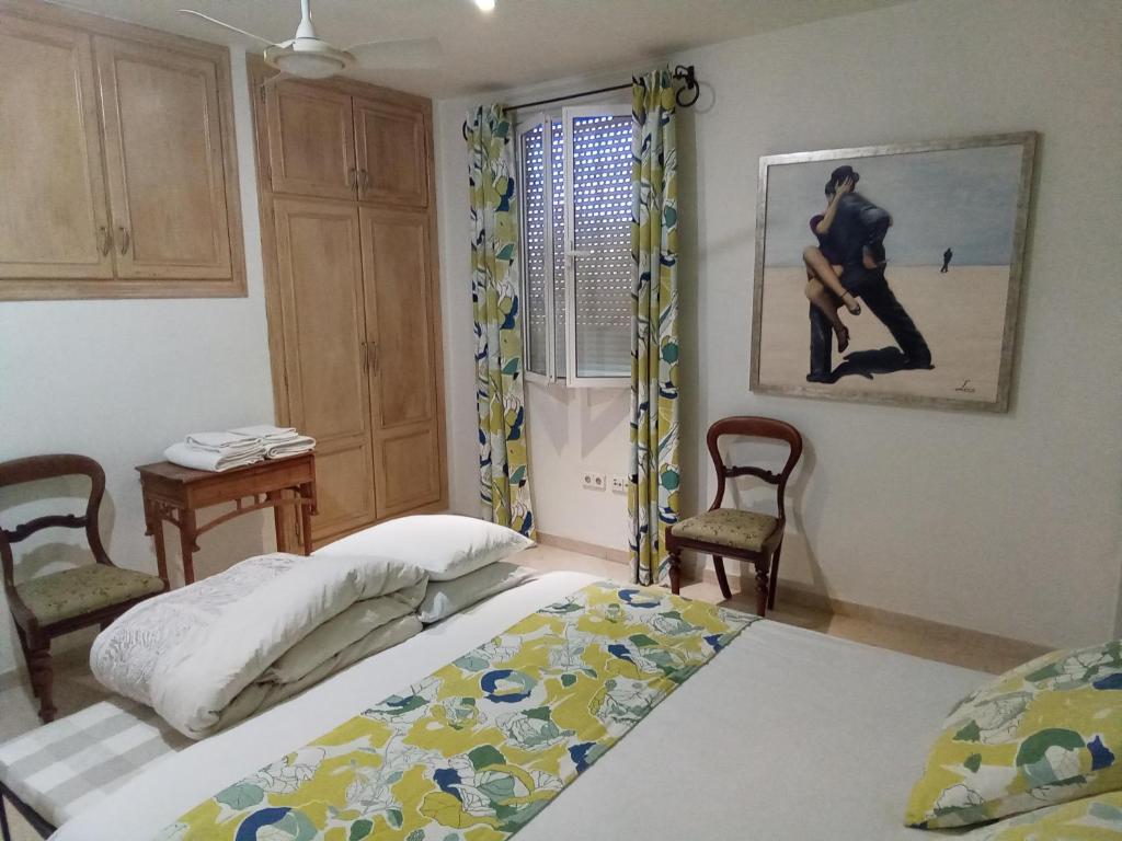 sypialnia z dwoma łóżkami i obrazem na ścianie w obiekcie Casa Romana w mieście Coín