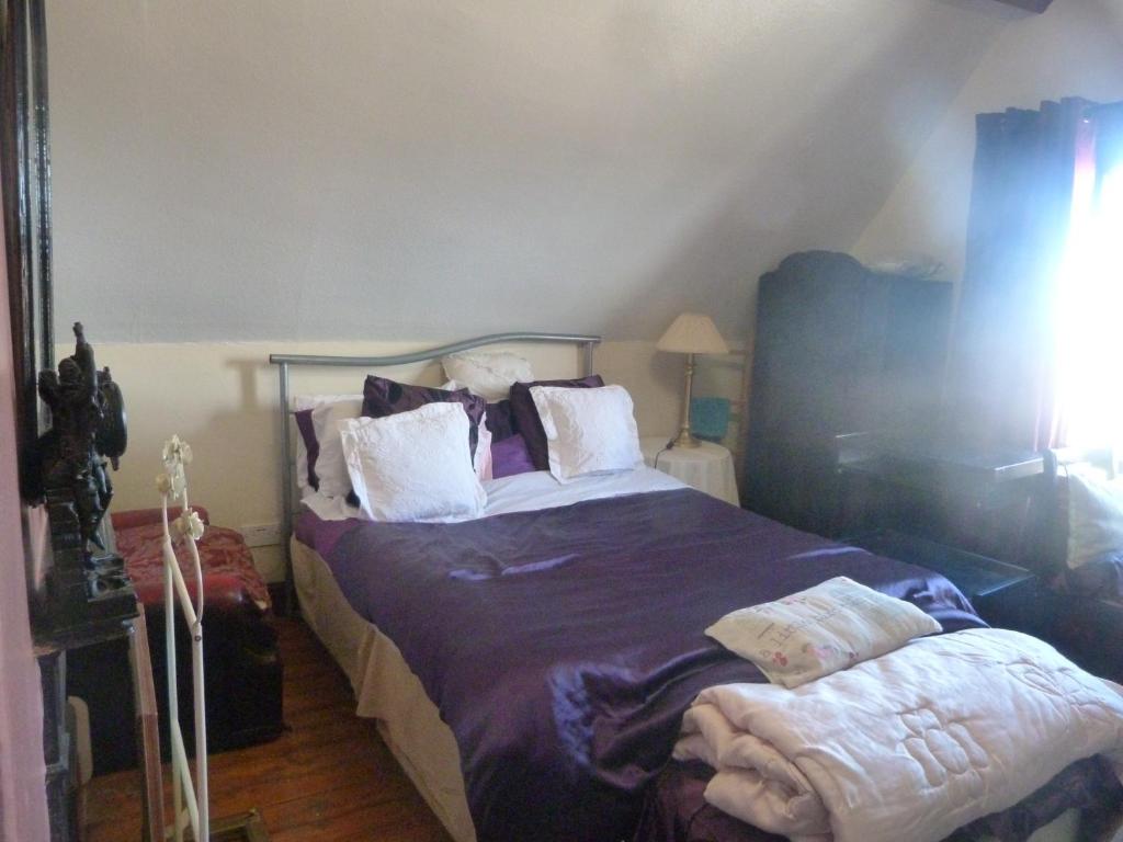 Ms McCreadys Guest House في دونكاستير: غرفة نوم مع سرير بملاءات ووسائد أرجوانية