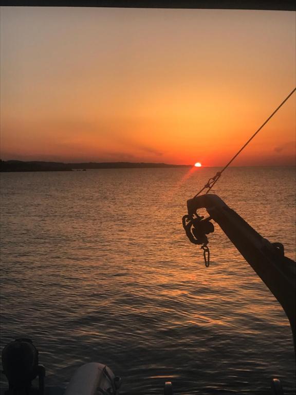 a person holding a fishing pole on a boat at sunset at NIGHT ON BOARD in La Maddalena
