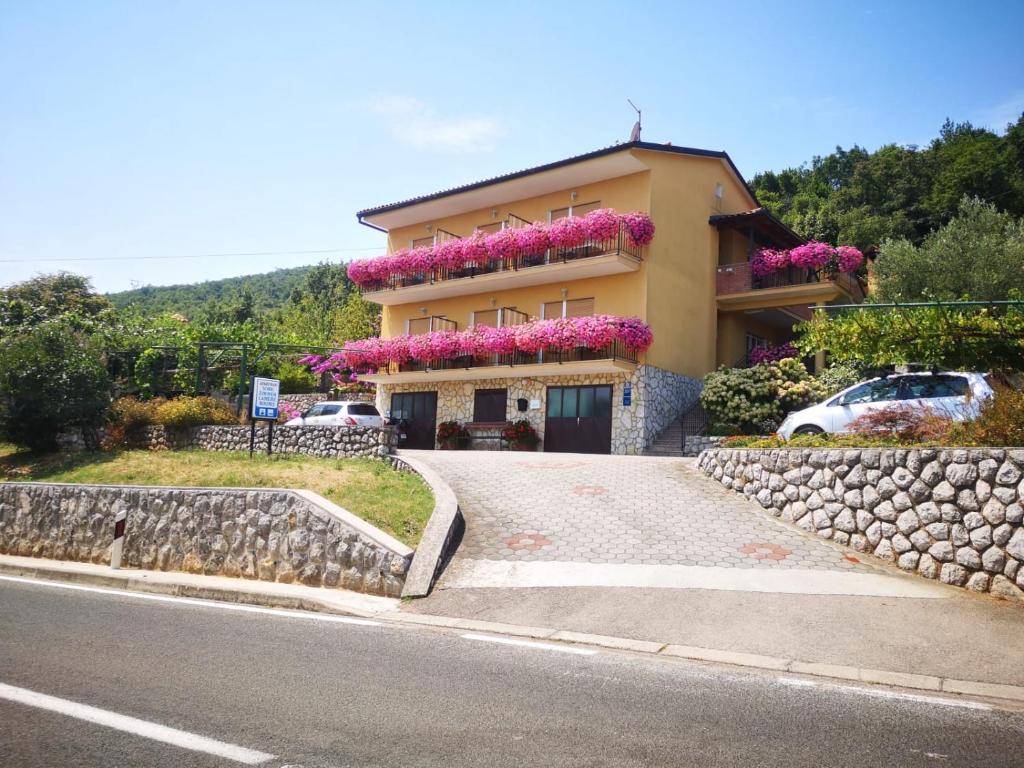a house with flowers on the side of a road at Holiday Home, Apartment and Rooms Milica in Mošćenička Draga