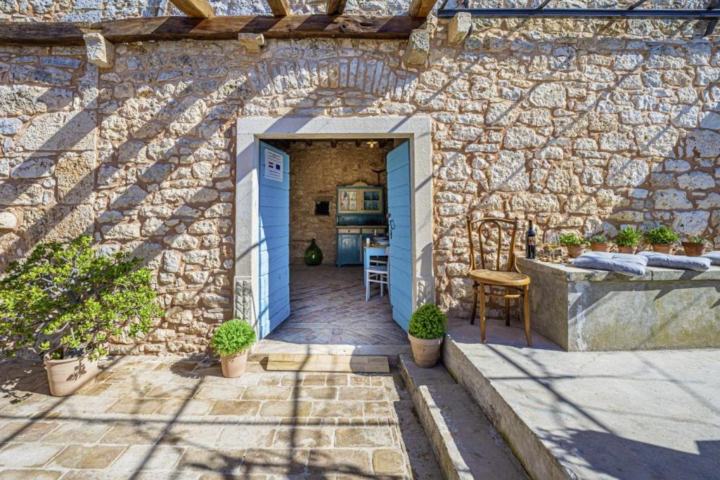 Casa de piedra con puerta azul y pared de piedra en Wine & Heritage - Johan i Matija in Grandići - Istrien en Grandići