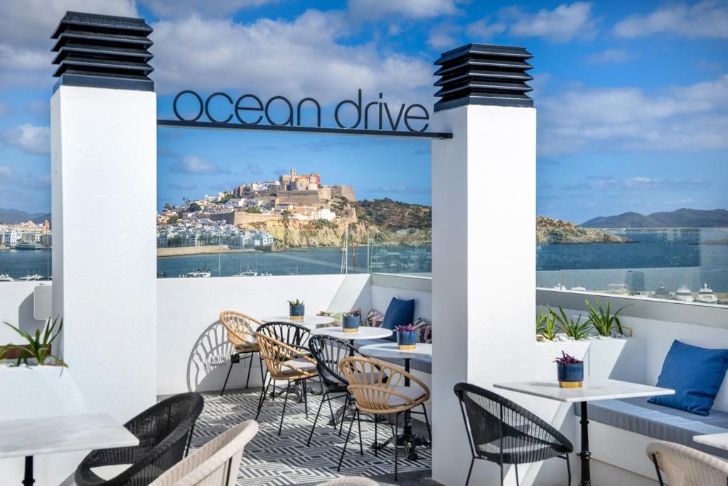 an outdoor patio with tables and chairs and a view of a castle at Ocean Drive Ibiza in Ibiza Town