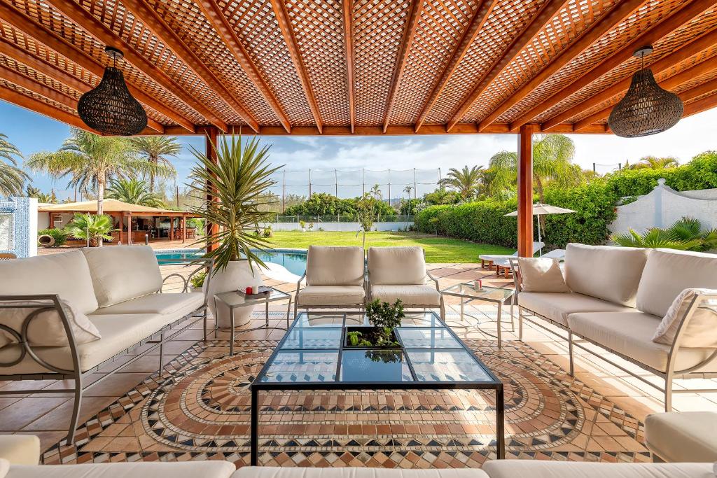 a patio with couches and a table and a pool at Luxury Villa Maspalomas Golf in Maspalomas