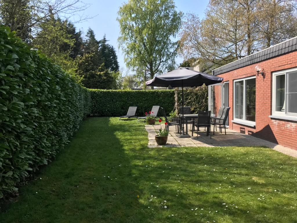 einen Garten mit einem Sonnenschirm, einem Tisch und Stühlen in der Unterkunft Hello Zeeland - Vakantiehuis Het Heem 39 in Breskens