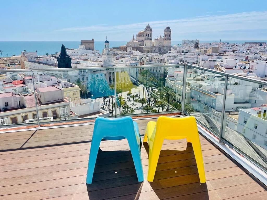 Duas cadeiras coloridas sentadas em cima de uma varanda em Skyline - Penthouse with 50m2 private terrace and stunning views em Cádis