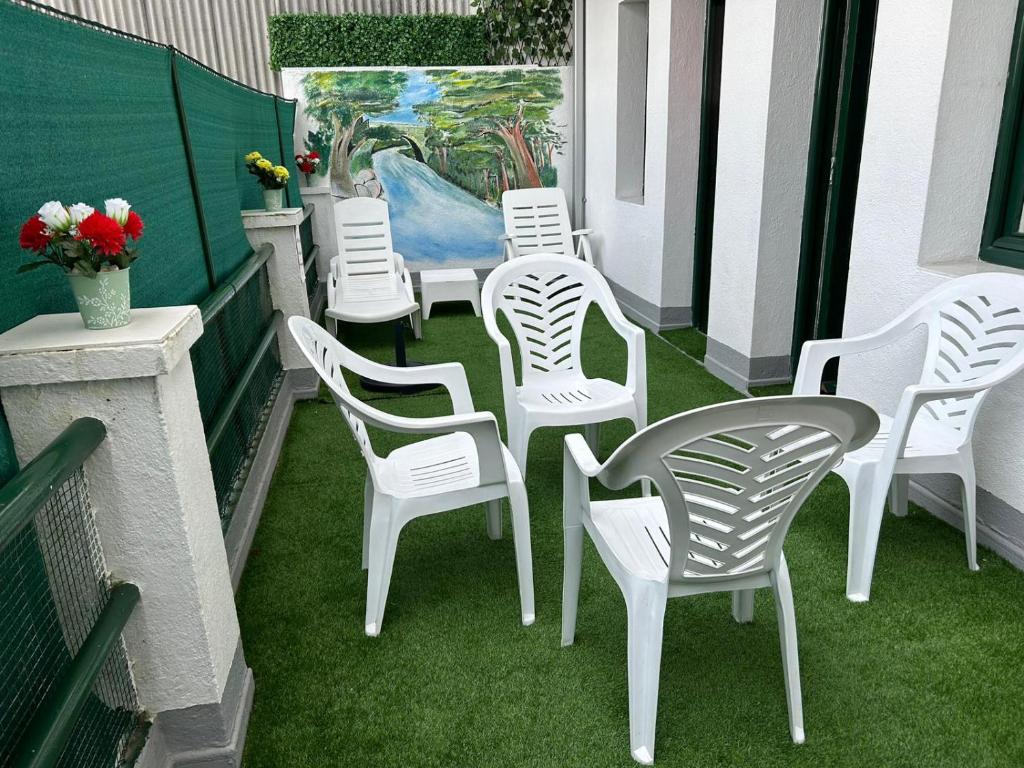 un grupo de sillas y mesas blancas en un balcón en Apartamento Salomé, en Padrón