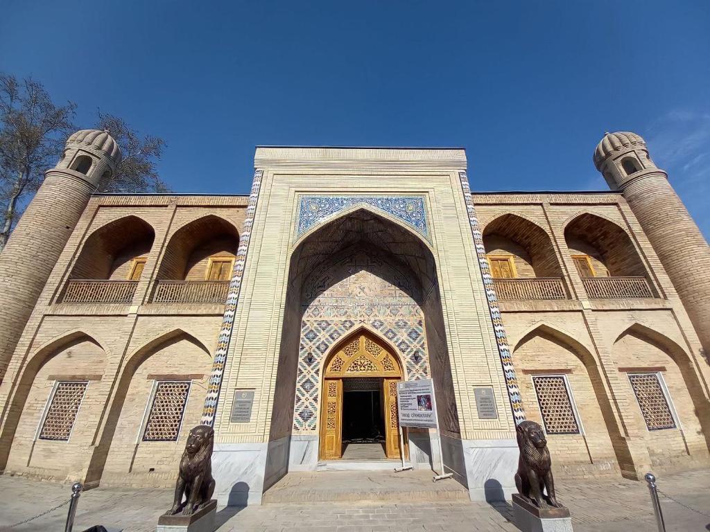 um grande edifício com uma porta com duas estátuas na frente em Rassom Hostel em Samarkand