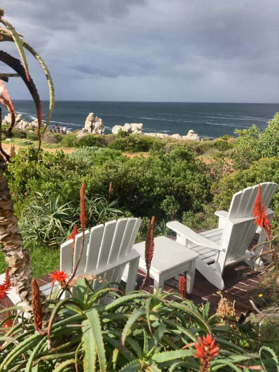 two white chairs sitting on a deck near the ocean at Rondawel with sea view in Kleinmond
