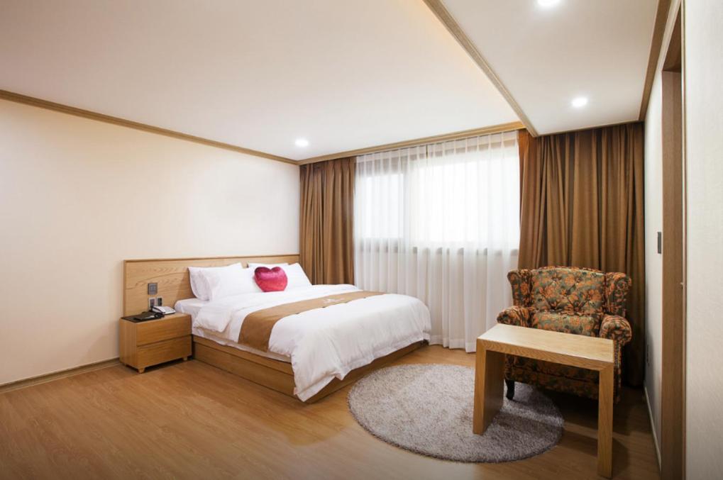 済州市にあるSH Nohyung Stayのベッドと椅子付きのホテルルーム