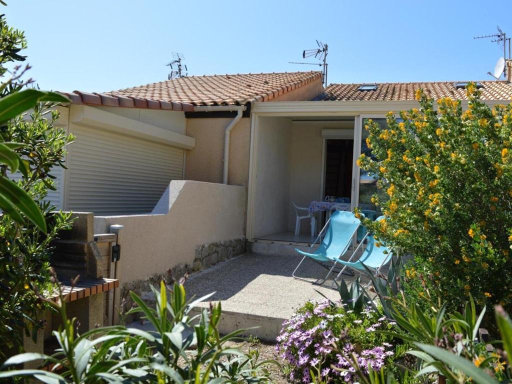 a house with a blue chair on a patio at Maison Fleury-Saint-Pierre-la-Mer, 1 pièce, 4 personnes - FR-1-229D-239 in Saint Pierre La Mer