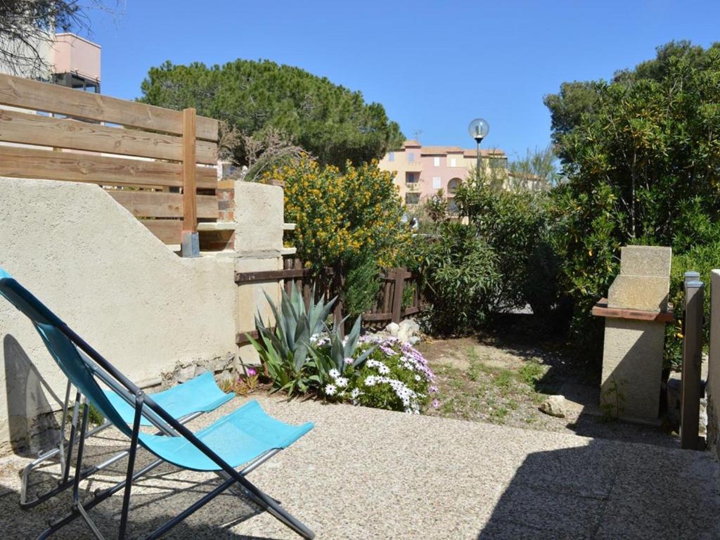 une chaise bleue assise au sol dans un jardin dans l'établissement Studio Cabine Mezzanine 4 Pers avec Piscine et Parking - Proche Plage et Centre à Saint Pierre La Mer - FR-1-229D-239, à Saint Pierre La Mer