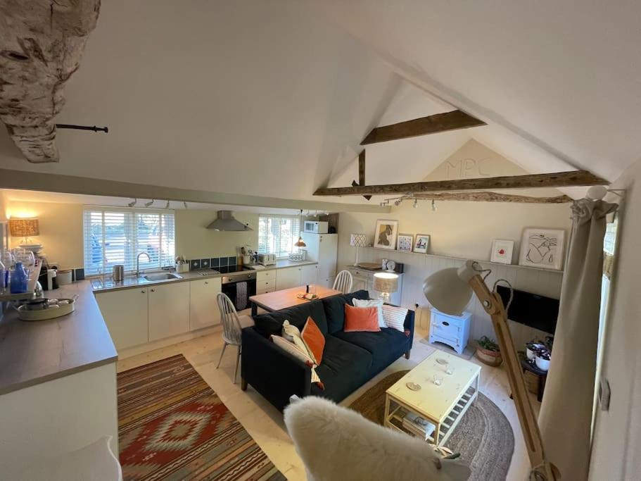 a living room with a couch and a kitchen at Mustard Pot Cottage in Eye