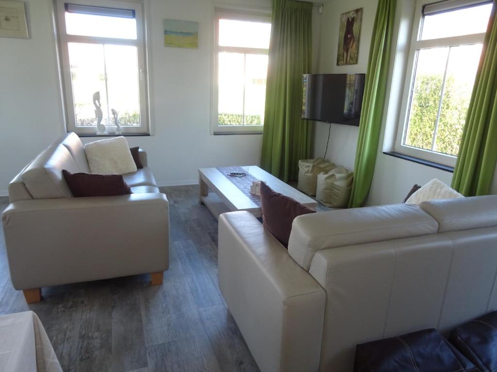 ein Wohnzimmer mit 2 Sofas und einem TV in der Unterkunft Kustverhuur, Landgoed de Lente in Breskens