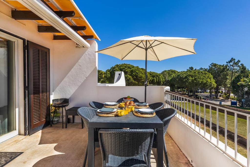 a table on a balcony with an umbrella at Apartament Portes Balaia in Albufeira