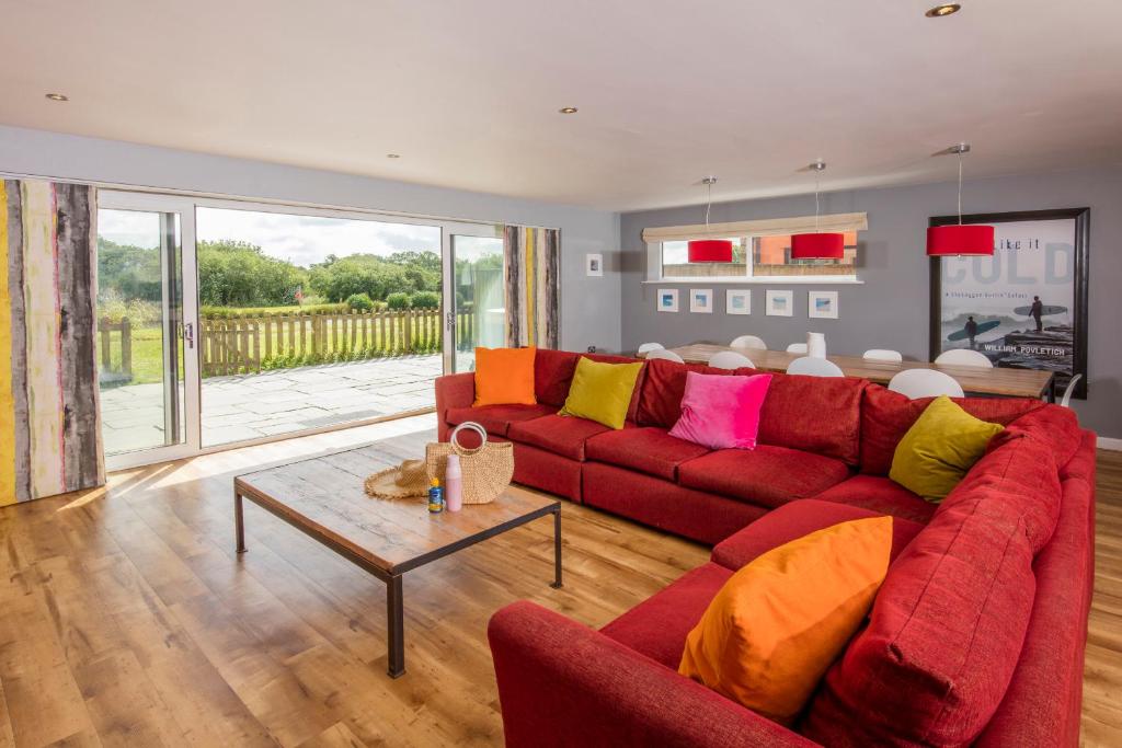 a living room with a red couch and a table at PointBreak Sleeps 12 with hot tub-Great celebration house-Dog friendly in Padstow