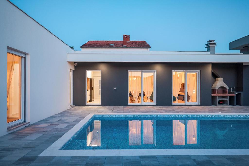 a swimming pool in front of a house at La Reina House - Private Heated Pool in Bibinje