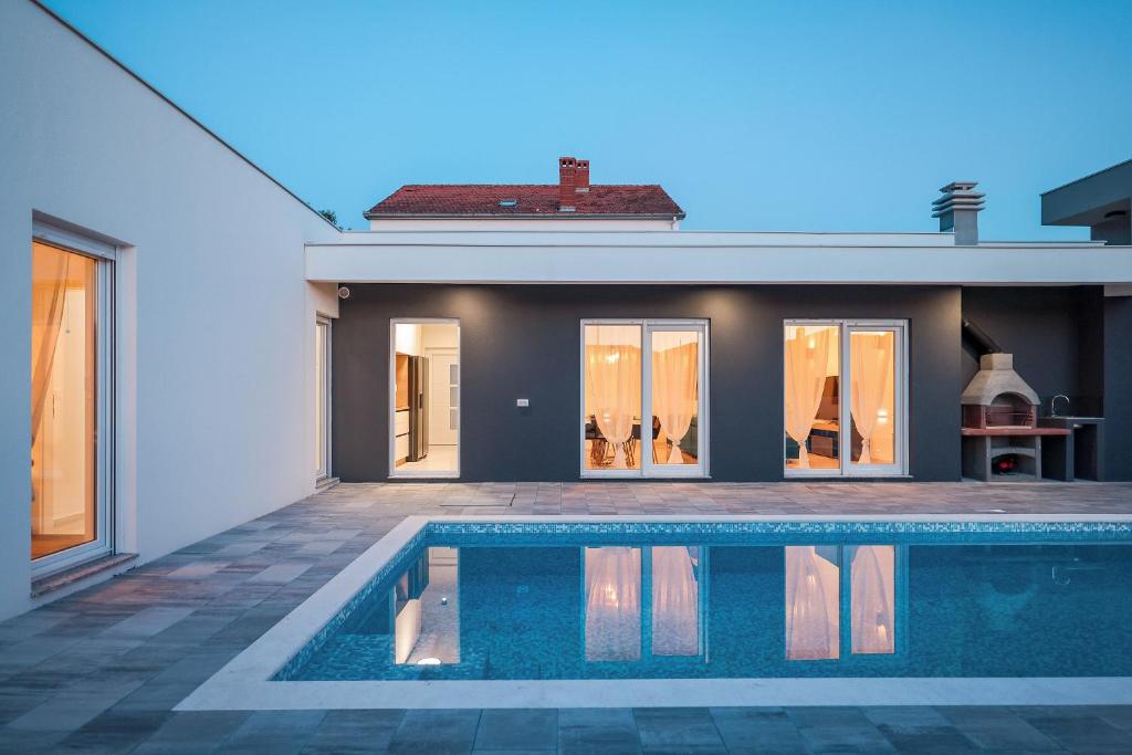 a swimming pool in front of a house at Villa La Reina - Private Heated Pool & Garden in Bibinje