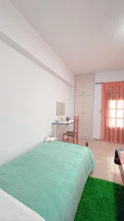 a bedroom with a green bed in a room with a table at Villa Maria (3) in Paleokastritsa