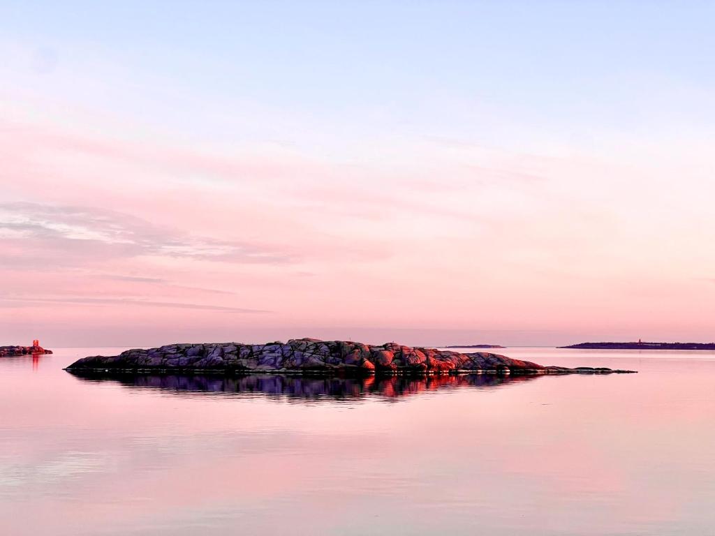 a small island in the water at sunset at Suite Portus - Design apartment by the sea in Hanko