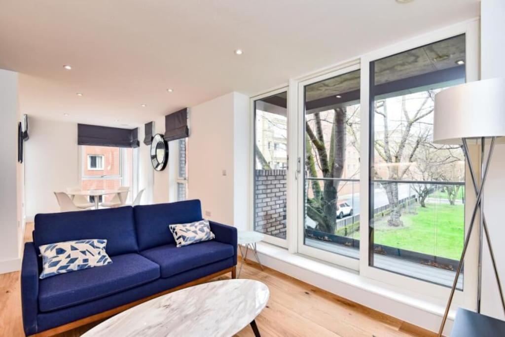 a living room with a blue couch and large windows at Luxury 2 Bedroom 2 bathroom Apartment -Borough Market/ London Bridge in London