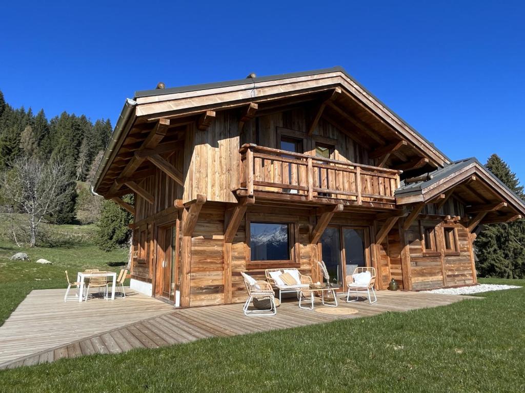 a large log cabin with a deck and chairs at Chalet Vue Mont-Blanc imprenable in Combloux
