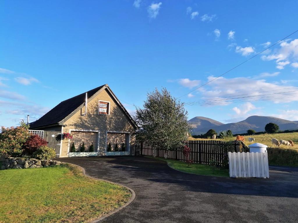 a house with a fence and mountains in the background at Mourne Magic House-Riverside luxury in Newcastle in Newcastle