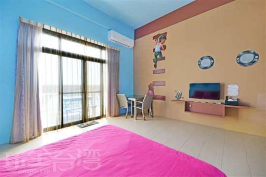 una camera con un grande letto rosa e una TV di Enjoy Summer a Magong