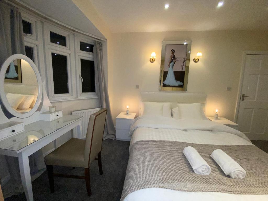 sypialnia z łóżkiem, biurkiem i lustrem w obiekcie Beautiful large 6 bedroom house up to 14 people w mieście Hendon
