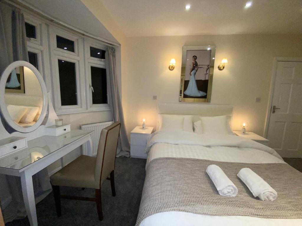 a bedroom with a bed and a desk and a mirror at Beautiful large 6 bedroom house up to 14 people in Hendon