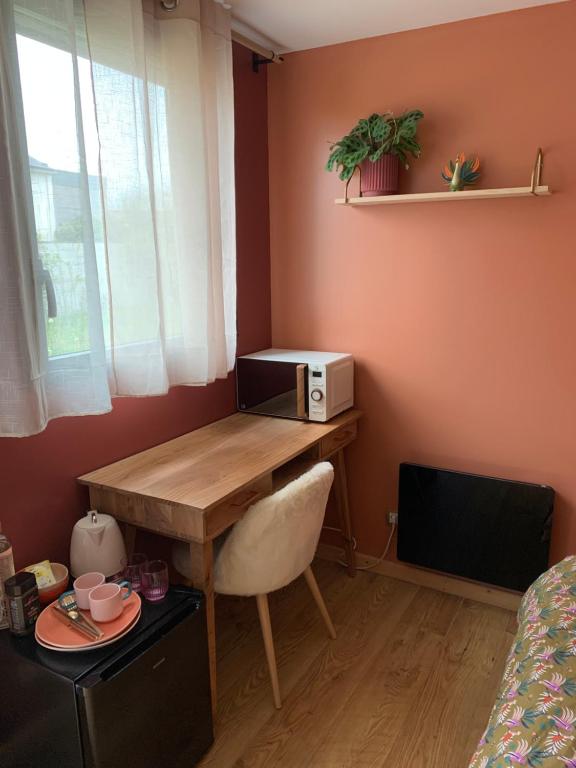 een kamer met een bureau en een magnetron. bij Chambre avec entrée privée in Saint-Renan
