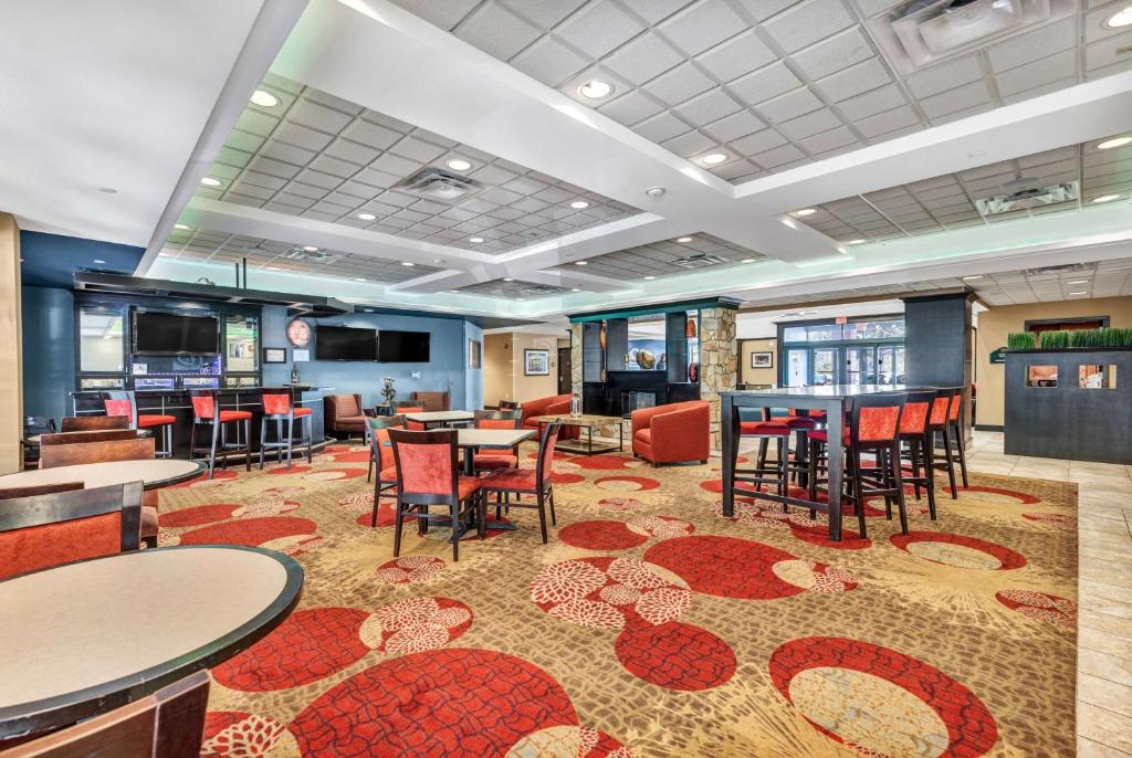 a restaurant with tables and chairs and a bar at Wingate by Wyndham State Arena Raleigh/Cary Hotel in Raleigh