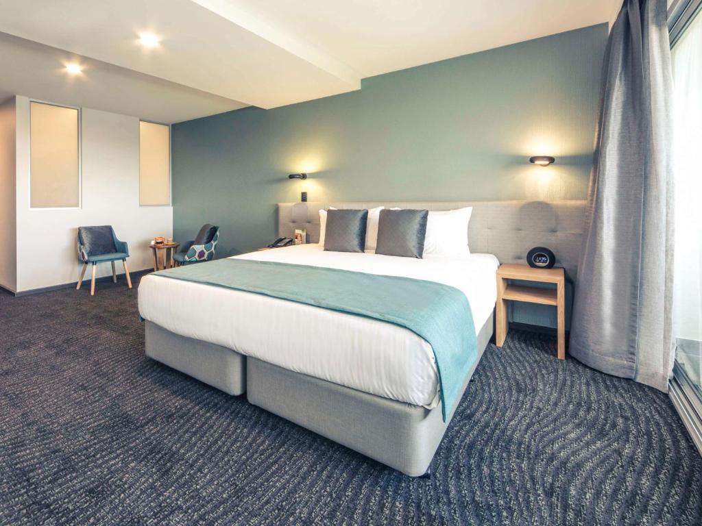 1 dormitorio con 1 cama grande y pared azul en Mercure Melbourne Caroline Springs en Caroline Springs
