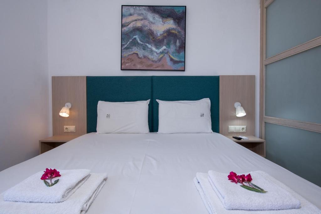 1 dormitorio con 1 cama blanca grande con flores rojas en las toallas en Elafonisi Village, en Elafonisi