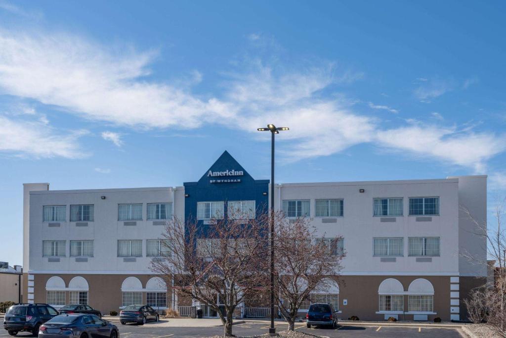 a building with cars parked in a parking lot at AmericInn by Wyndham Cedar Rapids North in Cedar Rapids