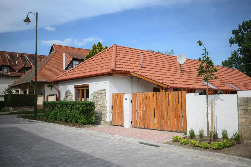 a house with an orange roof and a fence at Nana’s Vendégház in Mád