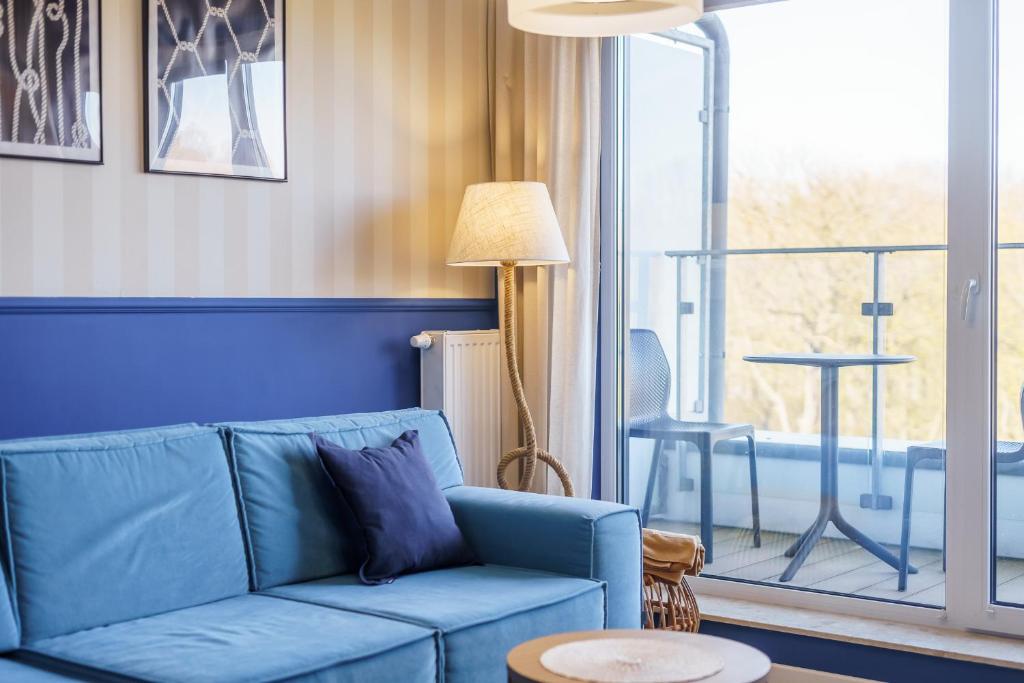 sala de estar con sofá azul y mesa en Apartamenty Fenomen - Horizon, Nadmorskie Tarasy FREE PARKING, SWIMMING POOL, SAUNA AND OTHER!, en Kołobrzeg
