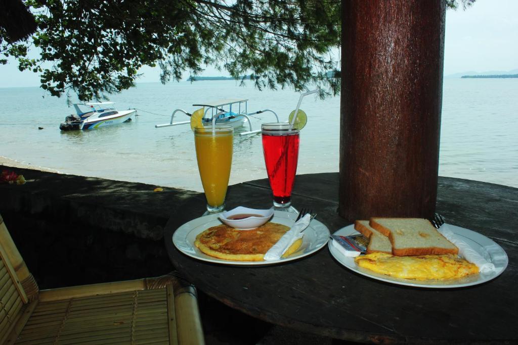 una mesa con dos platos de comida y dos bebidas en Krisna Bungalows and Restaurant, en Sekotong