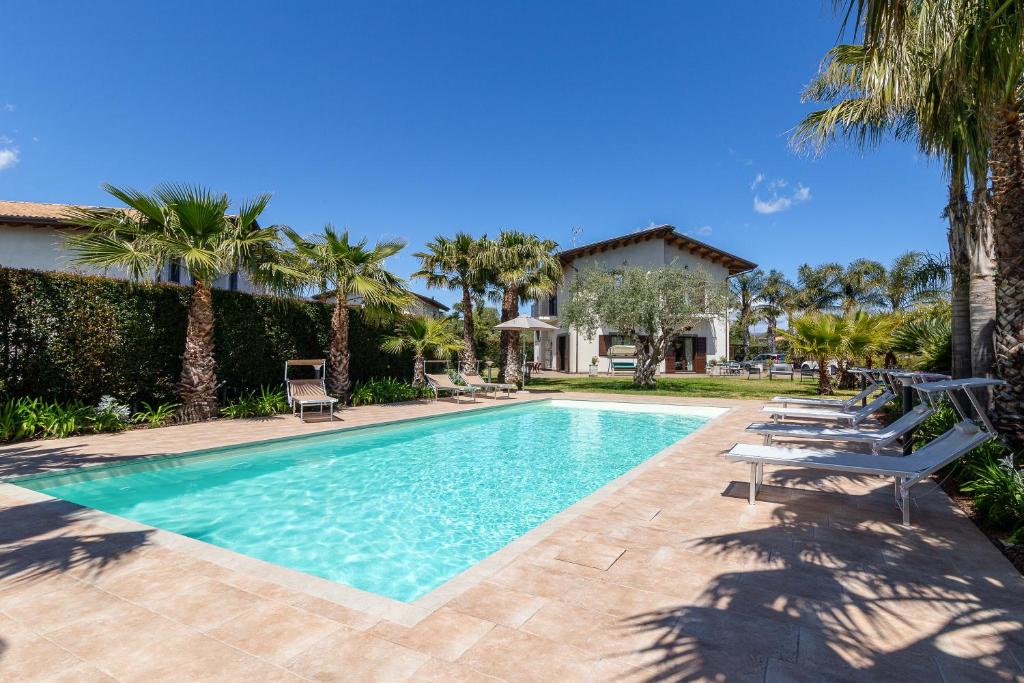 a swimming pool with lounge chairs and palm trees at Casa Il Geranio in Piedimonte Etneo