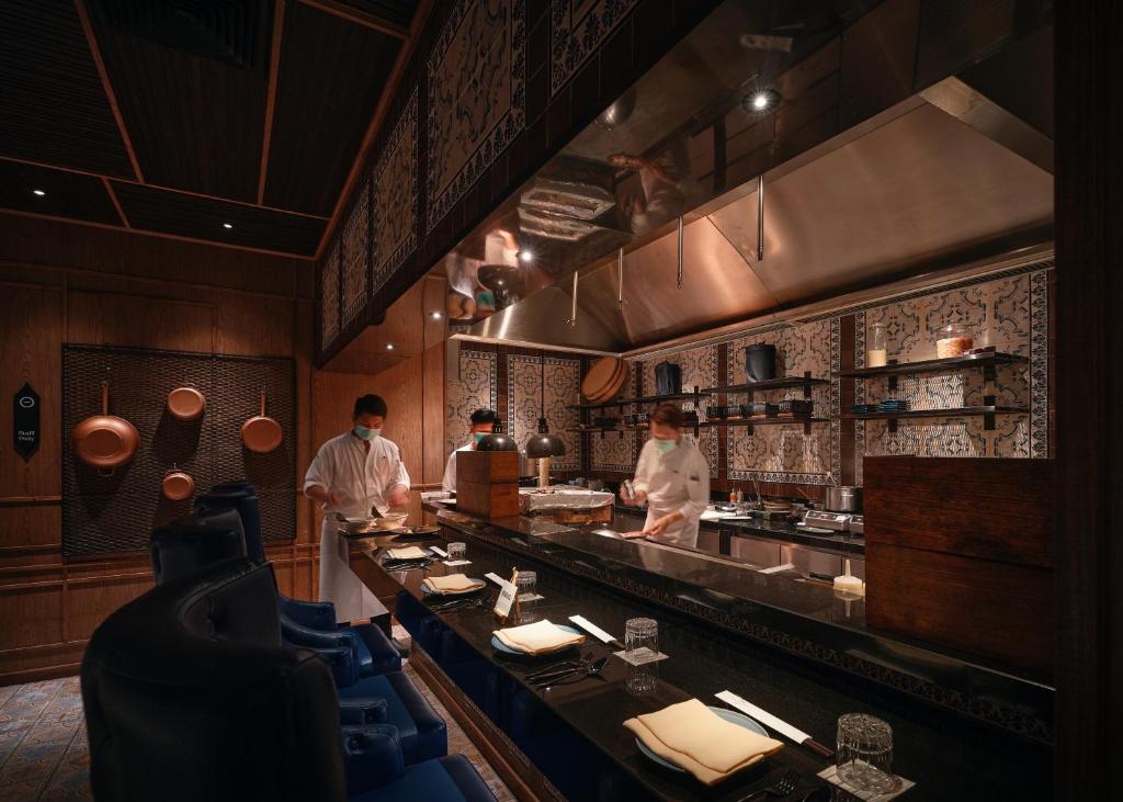 two chefs preparing food in a restaurant kitchen at InterContinental Phuket Resort by IHG in Kamala Beach