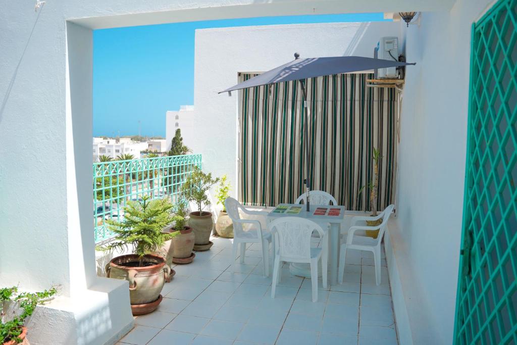 a balcony with a table and chairs and an umbrella at Appartement confortable proche plage et centre ville in Nabeul