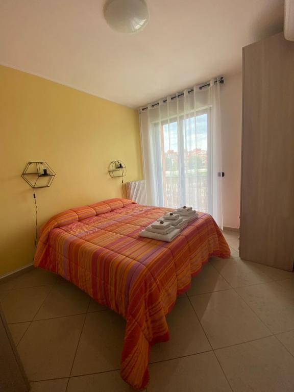 - une chambre avec un lit doté d'une couverture orange et d'une fenêtre dans l'établissement Appartamento Eliana, à Asti