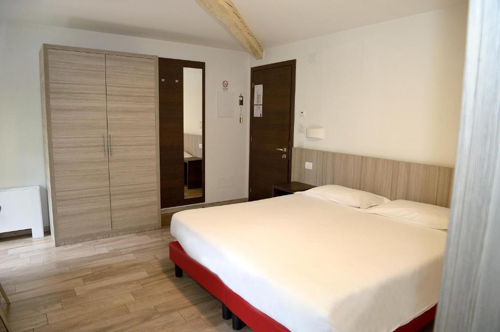 a bedroom with a large white bed and wooden floors at Break Affittacamere in San Vito al Tagliamento