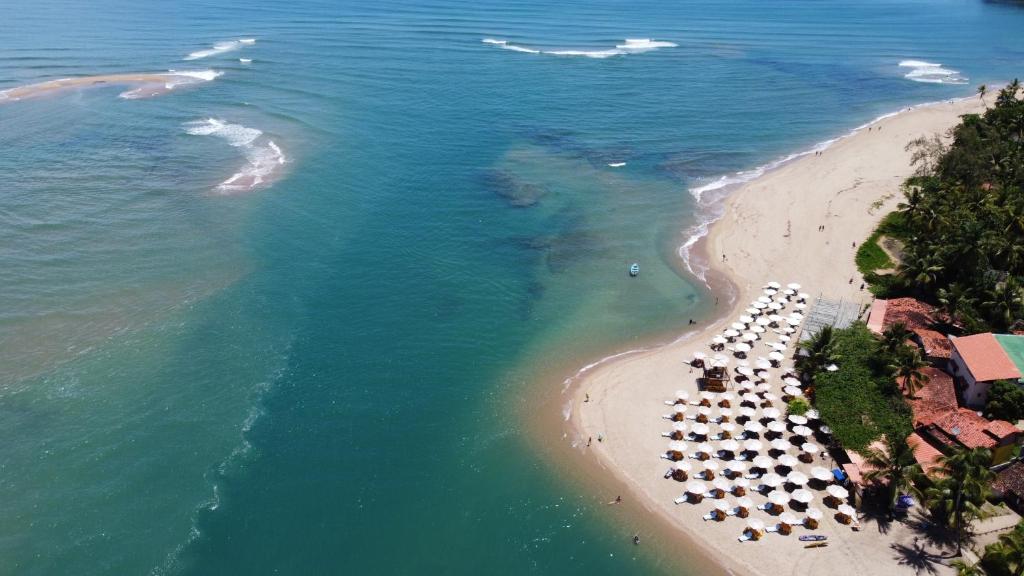 uma vista aérea de uma praia com guarda-sóis e do oceano em POUSADA TOCA DO LOBO na Ilha de Boipeba