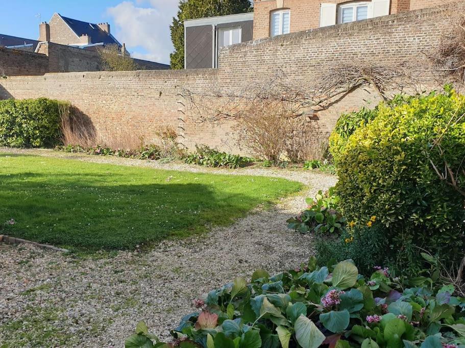 een tuin met een bakstenen muur en een aantal planten bij Marron 5 stars appartement in Amiens
