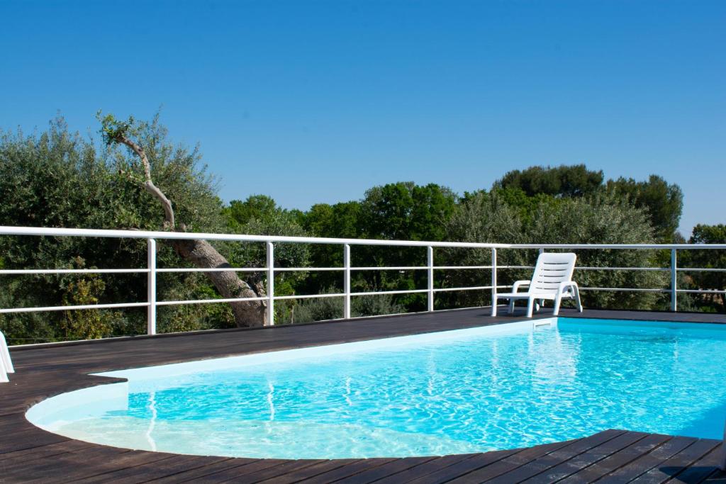 a swimming pool on a deck with a chair next to it at Casale dello Zio, private pool by IL PUMO DI PUGLIA in Castellana Grotte