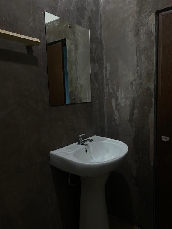 een badkamer met een witte wastafel en een spiegel bij Rustique House dbl in Nuwara Eliya