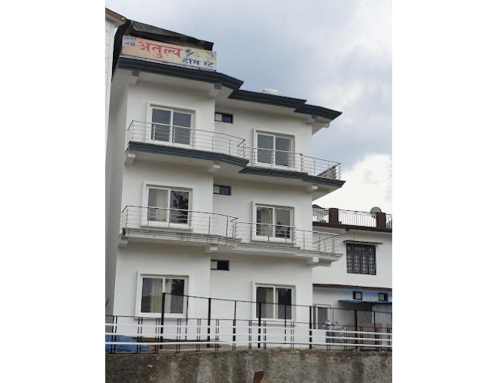 un edificio blanco con balcones en un lateral en Atulya Home Stay, Uttarkashi, en Dharāsu