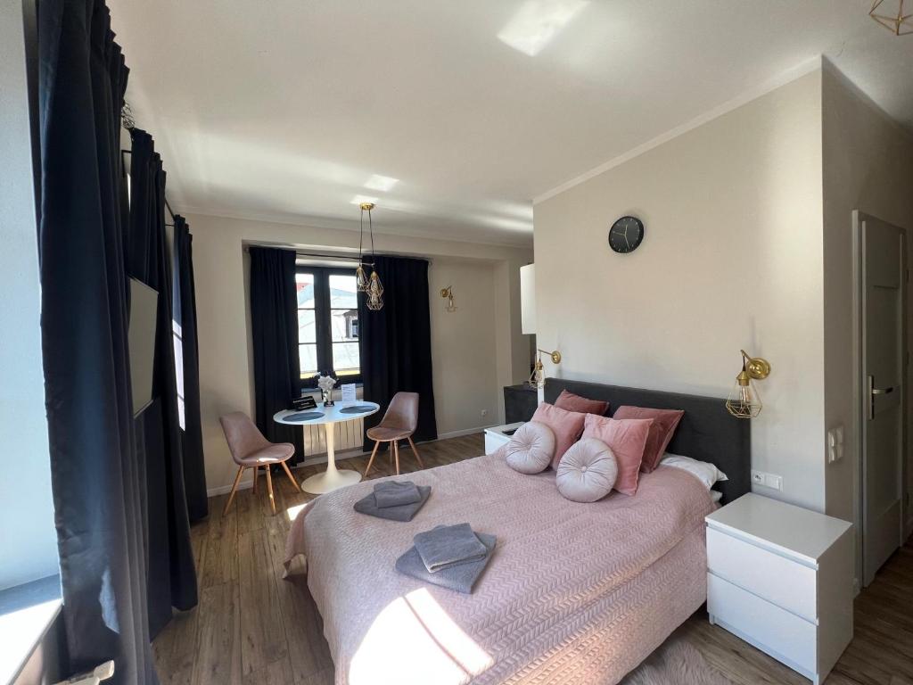 1 dormitorio con 1 cama grande con almohadas rosas en Apartamenty Łowicz, en Łowicz